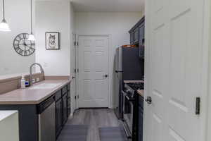 Kitchen with stainless steel dishwasher, pendant lighting, gas stove, sink, and dark hardwood / wood-style floors