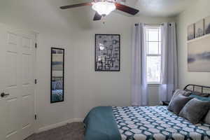 Carpeted bedroom featuring ceiling fan and a textured ceiling