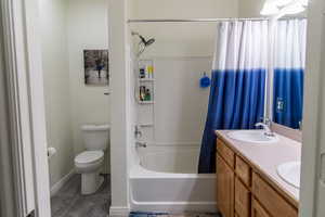 Full bathroom with toilet, vanity, and shower / bath combination with curtain