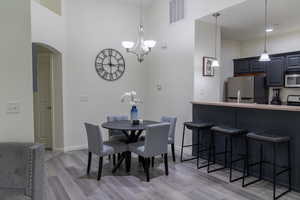 Dining area with light hardwood / wood-style floors, a chandelier, and a high ceiling