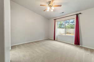 Carpeted spare room with ceiling fan and vaulted ceiling