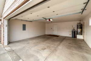 Garage featuring electric panel, gas water heater, and a garage door opener