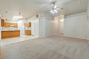 Unfurnished living room with a textured ceiling, ceiling fan, high vaulted ceiling, light carpet, and sink