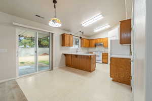 Kitchen with lofted ceiling, sink, white range with gas stovetop, kitchen peninsula, and hanging light fixtures