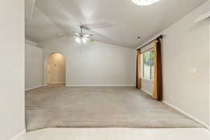 Spare room featuring ceiling fan, light colored carpet, and lofted ceiling