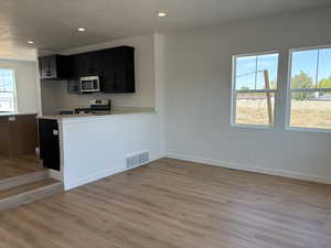 Kitchen featuring appliances with stainless steel finishes, light hardwood / wood-style flooring, and kitchen peninsula