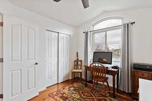 Home office with hardwood / wood-style flooring, ceiling fan, and vaulted ceiling