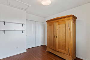 Unfurnished bedroom with dark hardwood / wood-style flooring and a closet