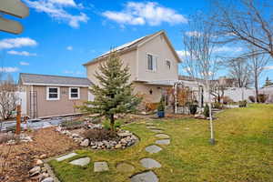 Rear view of house featuring a pergola, an outdoor structure, and a lawn