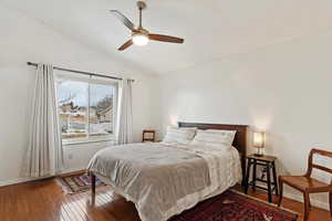 Bedroom with ceiling fan, vaulted ceiling, and wood-type flooring