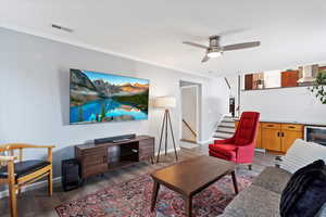 Living room with wine cooler, light hardwood / wood-style floors, ceiling fan, and ornamental molding