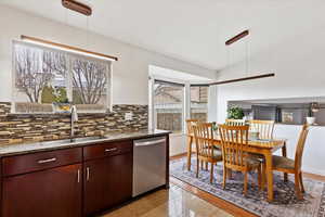 Kitchen with decorative backsplash, sink, stainless steel dishwasher, and decorative light fixtures