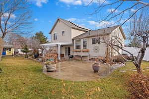 Back of property with a pergola, a patio area, and a lawn