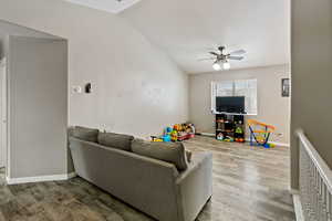 Living room featuring hardwood / wood-style flooring, vaulted ceiling, and ceiling fan