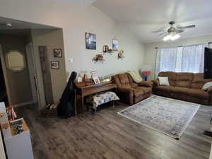 Living room with lofted ceiling, dark hardwood / wood-style floors, and ceiling fan