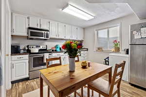 Kitchen with white cabinetry, appliances with stainless steel finishes, and light hardwood / wood-style flooring