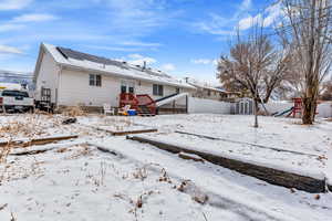 Snow covered house with a storage unit and a playground