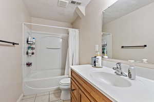 Full bathroom featuring tile patterned floors, shower / bath combo with shower curtain, toilet, and vanity