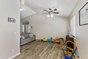 Game room featuring ceiling fan, plenty of natural light, vaulted ceiling, and hardwood / wood-style floors