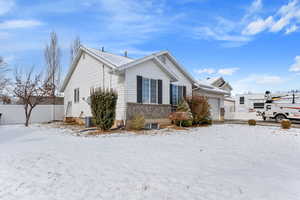 View of snowy exterior featuring a garage and central AC unit