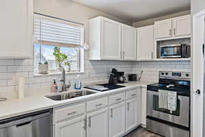 Kitchen with white cabinetry, stainless steel appliances, and sink