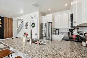 Kitchen featuring a kitchen breakfast bar, stainless steel appliances, sink, white cabinetry, and kitchen peninsula