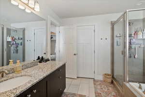 Bathroom with vanity, tile patterned flooring, and a shower with shower door