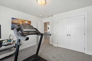 Exercise room with carpet floors and a textured ceiling