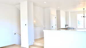 Kitchen with light wood-type flooring, sink, and a notable chandelier