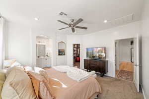 Bedroom with a closet, ensuite bath, ceiling fan, a walk in closet, and light colored carpet