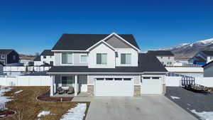 View of front of property featuring concrete driveway, stone siding, fence, a mountain view, and board and batten siding