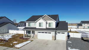 View of front facade with a fenced backyard, driveway, stone siding, a residential view, and board and batten siding