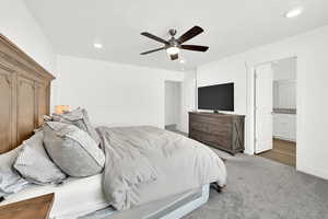 Carpeted bedroom featuring ensuite bathroom and ceiling fan