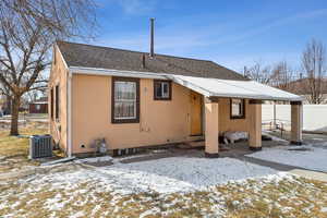 Snow covered rear of property with central AC unit