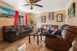 Tiled living room with ornamental molding and ceiling fan