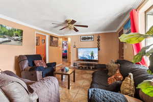 Tiled living room featuring ceiling fan and ornamental molding