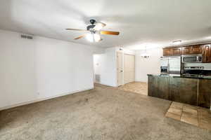 Kitchen with appliances with stainless steel finishes, hanging light fixtures, light colored carpet, and ceiling fan