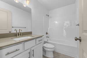 Full bathroom featuring bathtub / shower combination, toilet, vanity, and tile patterned flooring