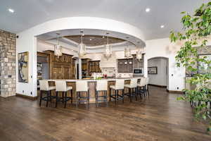 Kitchen with stainless steel microwave, a large island, decorative light fixtures, dark hardwood / wood flooring, and a breakfast bar area