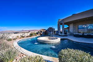 View of pool featuring an in ground hot tub, pool water feature, a mountain view, and a patio