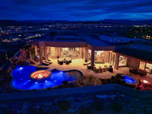 Pool at night featuring an in ground hot tub, a patio, and a fire pit