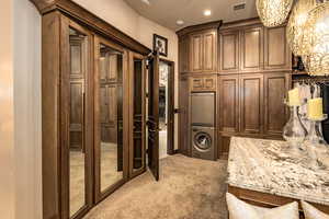 Interior space featuring stacked washer / dryer, refrigerator, a breakfast bar, light stone countertops, and light colored carpet