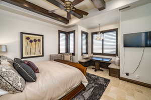 Bedroom with beam ceiling, built in desk, and an inviting chandelier