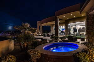 Pool at night featuring an in ground hot tub and a patio area