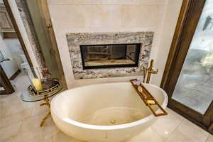 Bathroom featuring a tub to relax in, a tile fireplace, and tile patterned floors