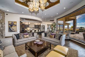 Living room featuring hardwood / wood-style flooring, a raised ceiling, and a dramatic chandelier