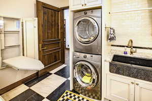 Laundry area with sink, cabinets, and stacked washer / dryer