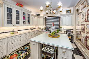 Kitchen featuring hanging light fixtures, a kitchen island, an inviting chandelier, tasteful backsplash, and a kitchen breakfast bar