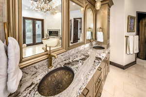 Bathroom with a multi sided fireplace, french doors, a tub to relax in, tile patterned floors, and vanity