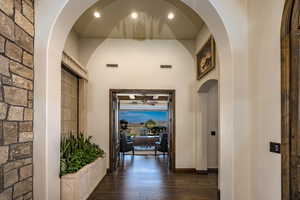 Corridor with dark hardwood / wood flooring and dramatic arch lead to the home office